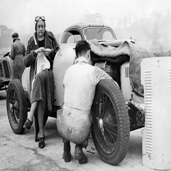 Holy Mackerel knitting between races retro black and white photographic card featuring a vintage image of a female racing driver stopping to knit by her car - 12.6 x 17.7cm and blank inside