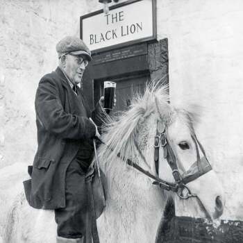 Holy Mackerel a pint at the pub retro black and white photographic card featuring a vintage image of an elderly rider having a beer on his horse - 12.6 x 17.7cm and blank inside